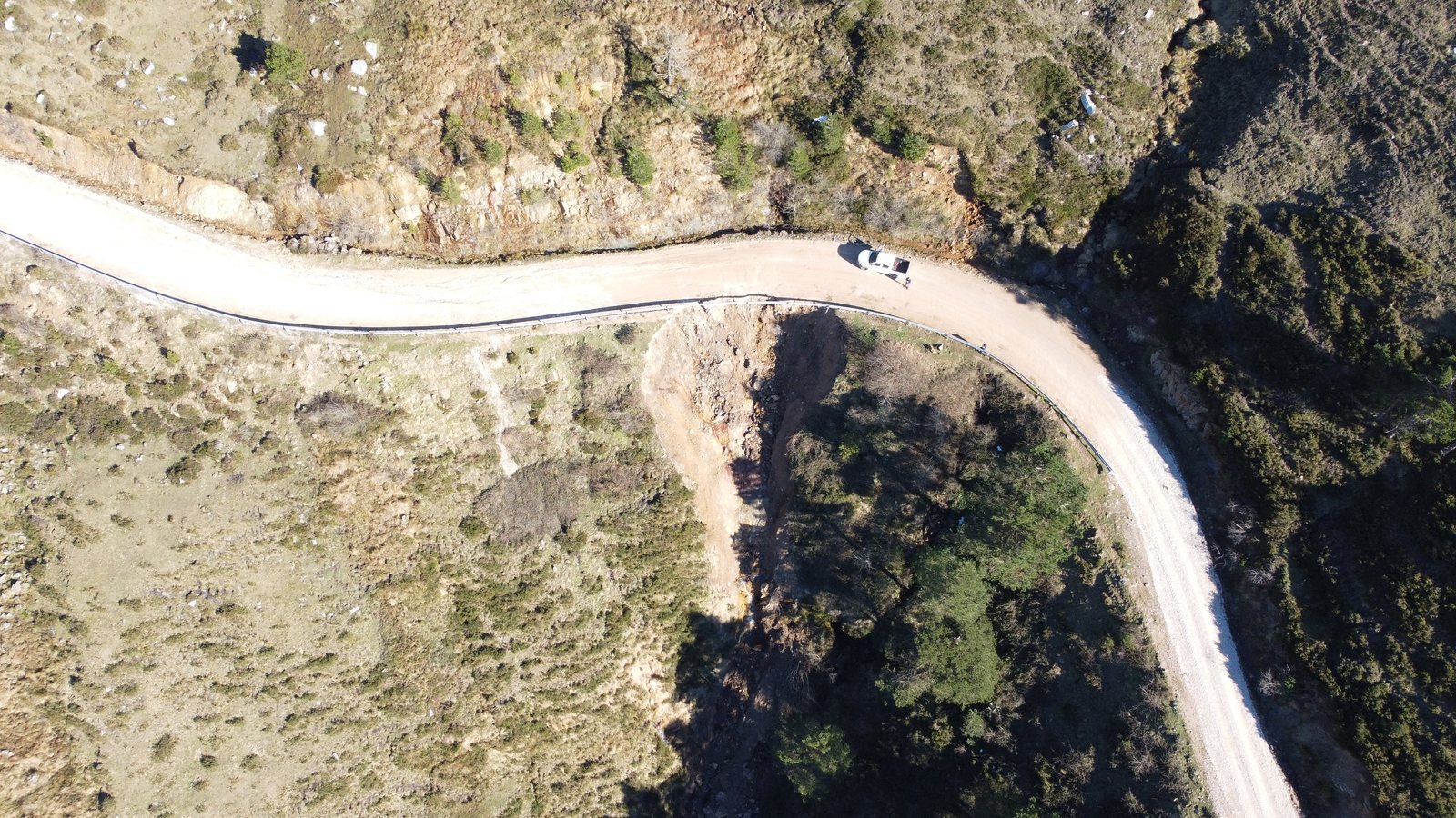 Vista cenital de un vial en ladera con desprendimiento del talud bajo la calzada